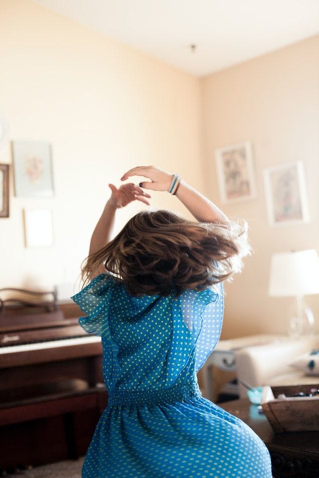 A girl wearing a blue dress dancing in the living room